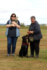 Susan holding a client’s Yorkshire Terrier and Lorna with Kol, her black Labrador.